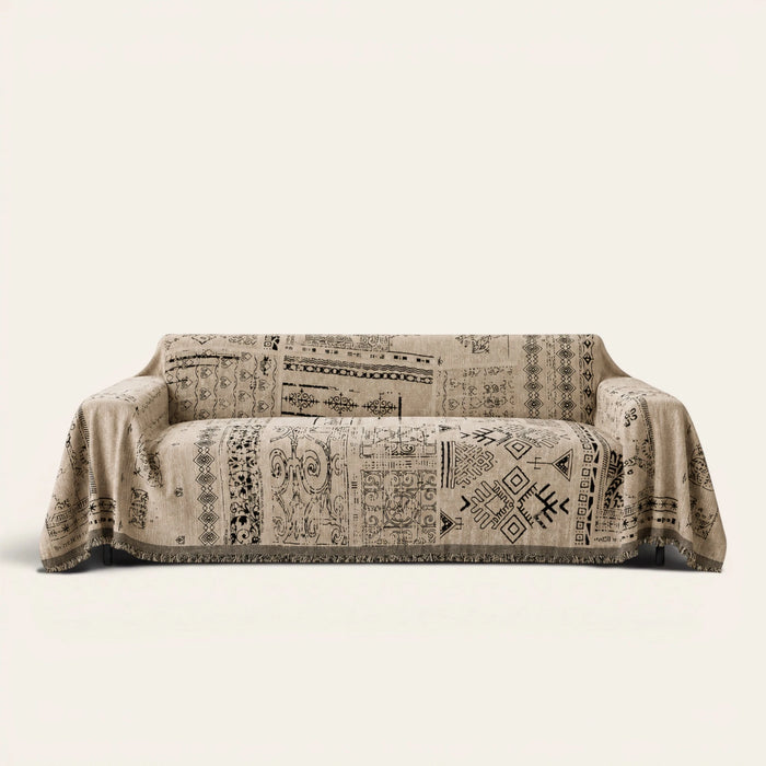 Sand Beige Artisan Glyph throw draped over a two-seat sofa on ivory background