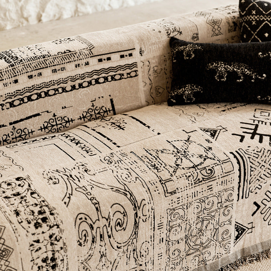 Detail of the sofa arm with the black glyph print and a leopard-motif cushion