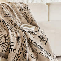Sand beige glyph throw draped across a cream sofa with an open book
