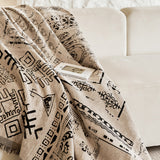 Sand beige glyph throw draped across a cream sofa with an open book