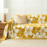 Golden bloom Bloom Elegance floral throw styled on a sofa with neutral cushions and a wood lamp table