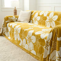 Angled view of the Bloom Elegance golden bloom throw over a sofa with a ribbed cushion and fringed hem