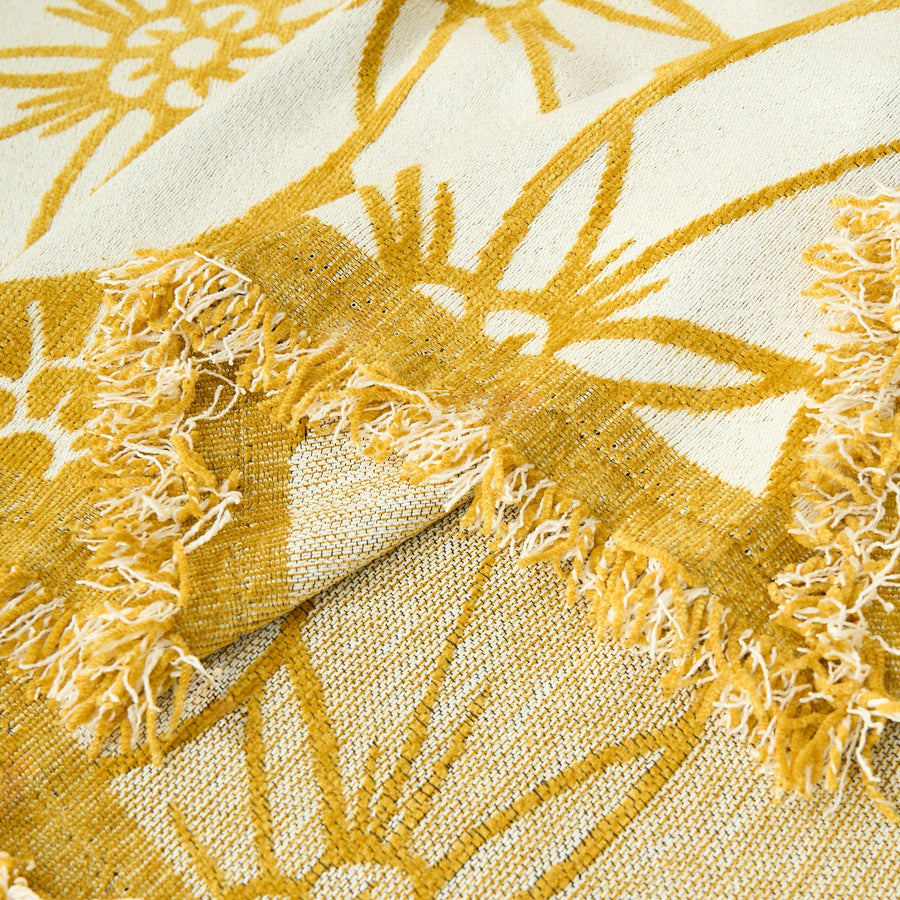 Close-up of the golden bloom throw's fringed edge and woven texture in mustard and cream floral