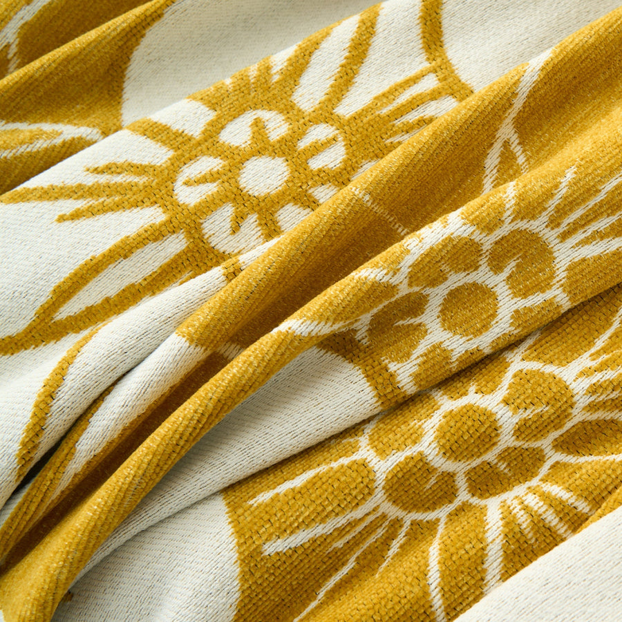Macro close-up of the golden bloom throw's soft chenille weave and bold daisy blossom motifs