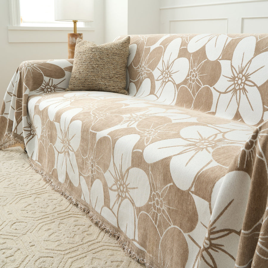 Angled view of Mocha Latte Bloom Elegance throw over a sofa with a cushion and lamp by a window