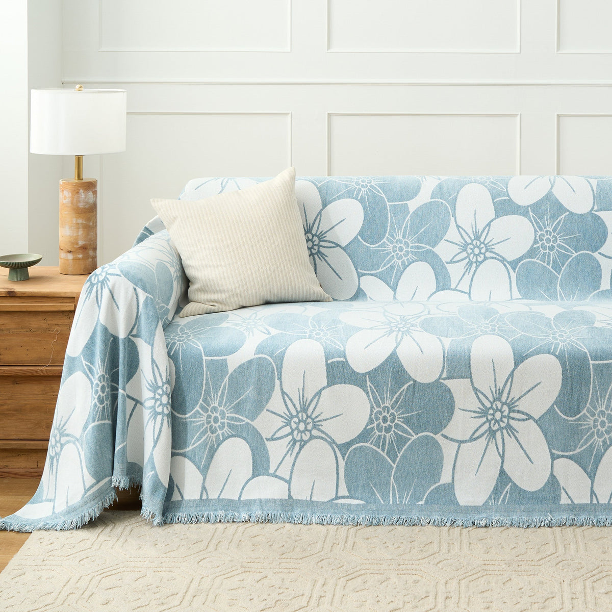 Ocean Bloom Bloom Elegance throw styled on a sofa with ribbed cream cushion and lamp