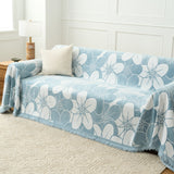 Ocean Bloom Bloom Elegance throw covering a sofa beside a wood table and lamp, wide view