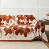 Rust floral blossom throw covering a sofa near a wood side table and panelled wall
