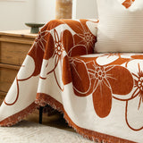 Close-up of the rust blossom throw draped over a sofa corner beside a wood chest