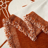 Detail of the fringed edge and woven texture of the rust floral throw