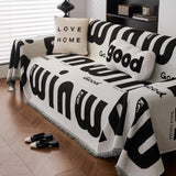 Front angle of the Bold Typography graphic harmony throw over a couch with lettered cushions and a bolster