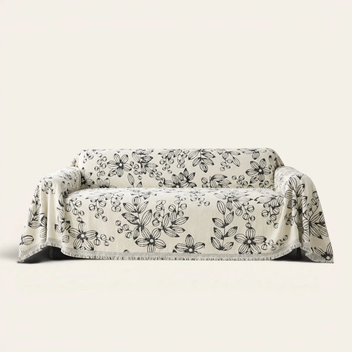 Botanic Bliss sofa throw in Botanic Sketch over a couch, front view with sketched black florals and fringe