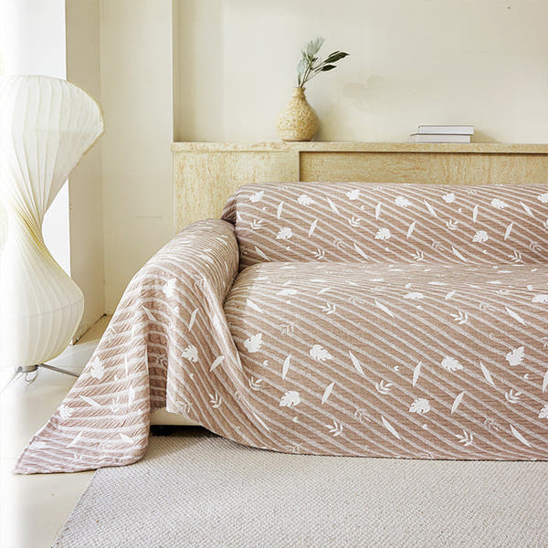 Linen Beige Botanical Quilted throw styled on a sofa with a vase and paper lamp in a bright room