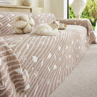 Angled view of Linen Beige Botanical Quilted throw draped over a sofa, a white cat curled with a teacup