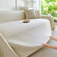Hands smoothing the Ivory Pearl Breeze Lattice throw over a sofa, lattice pattern in view