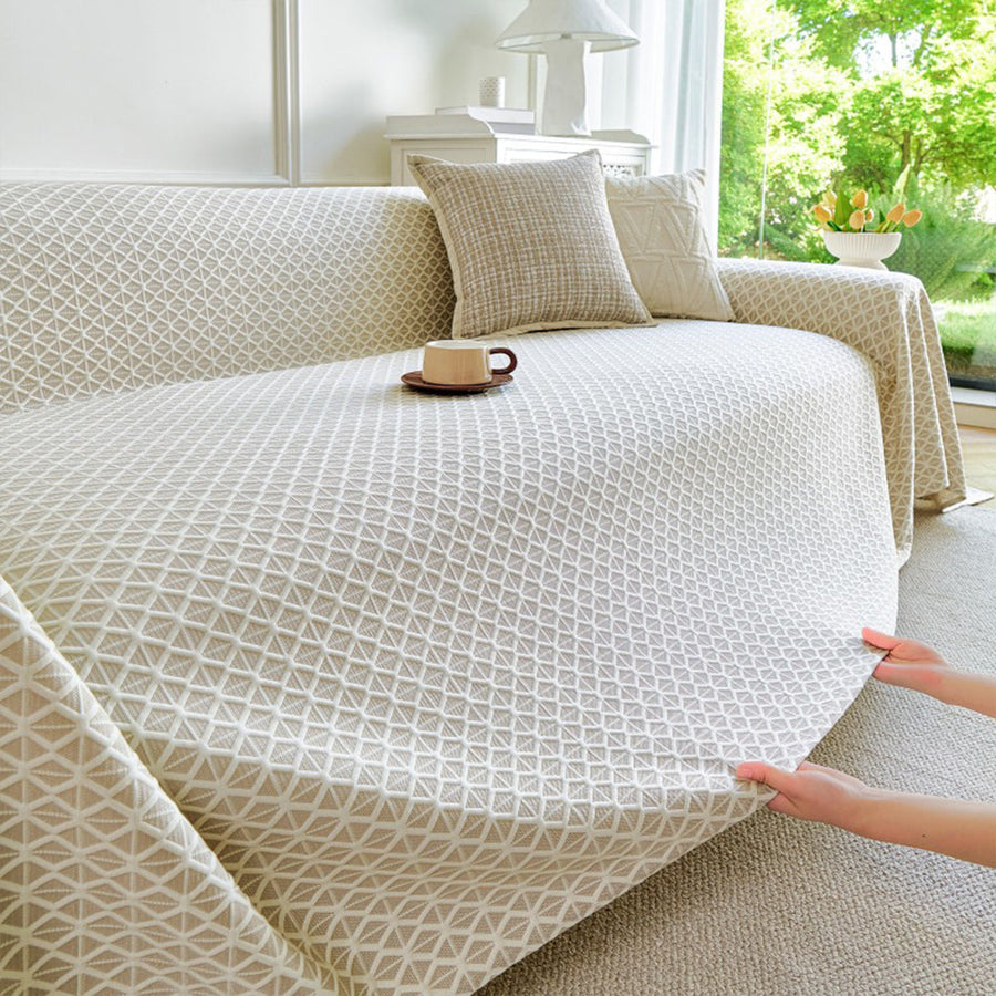 Hands smoothing the Ivory Pearl Breeze Lattice throw over a sofa, lattice pattern in view