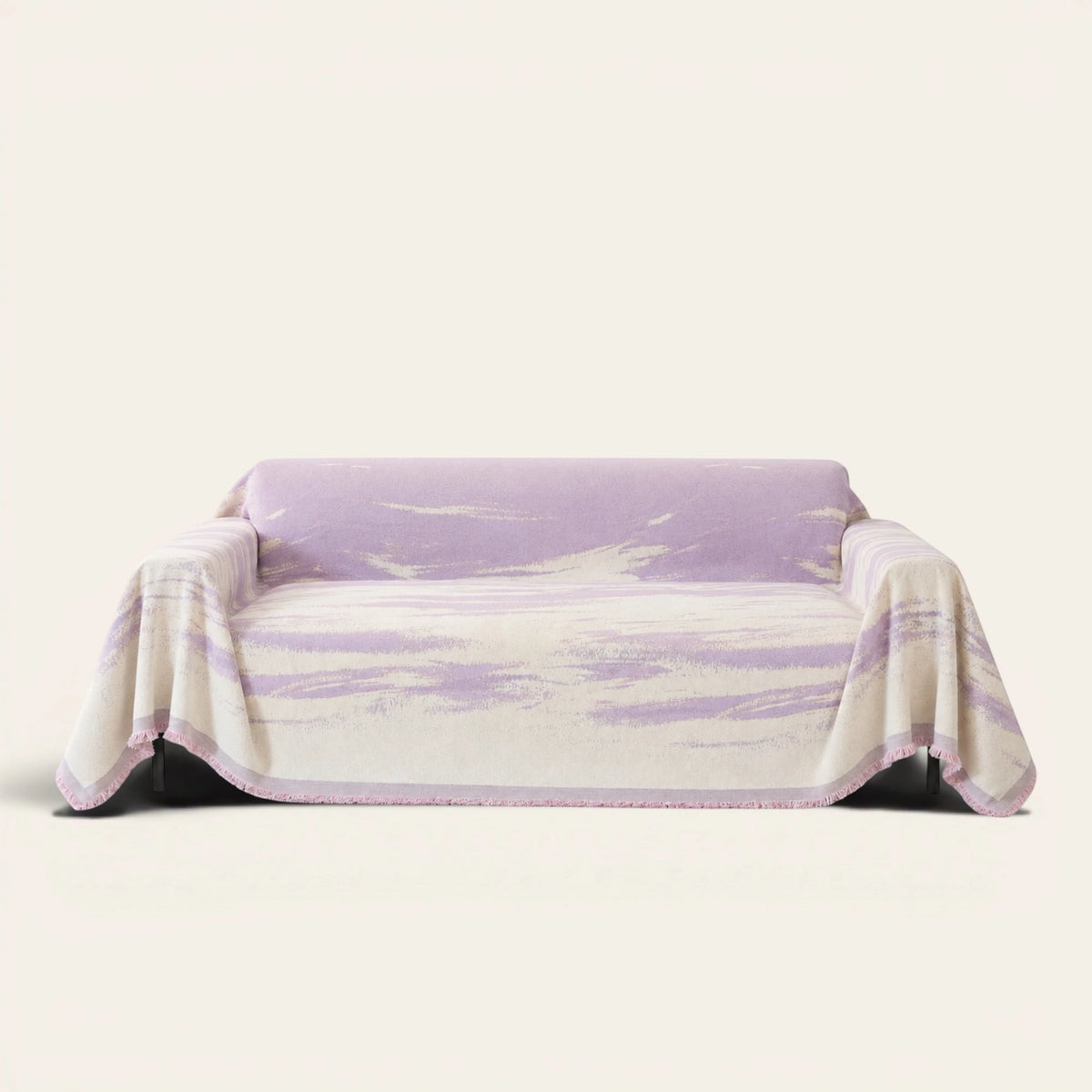 Lavender Drift Brushwave Chenille sofa throw draped over a two-seat sofa, front view on ivory background, pink fringed hem