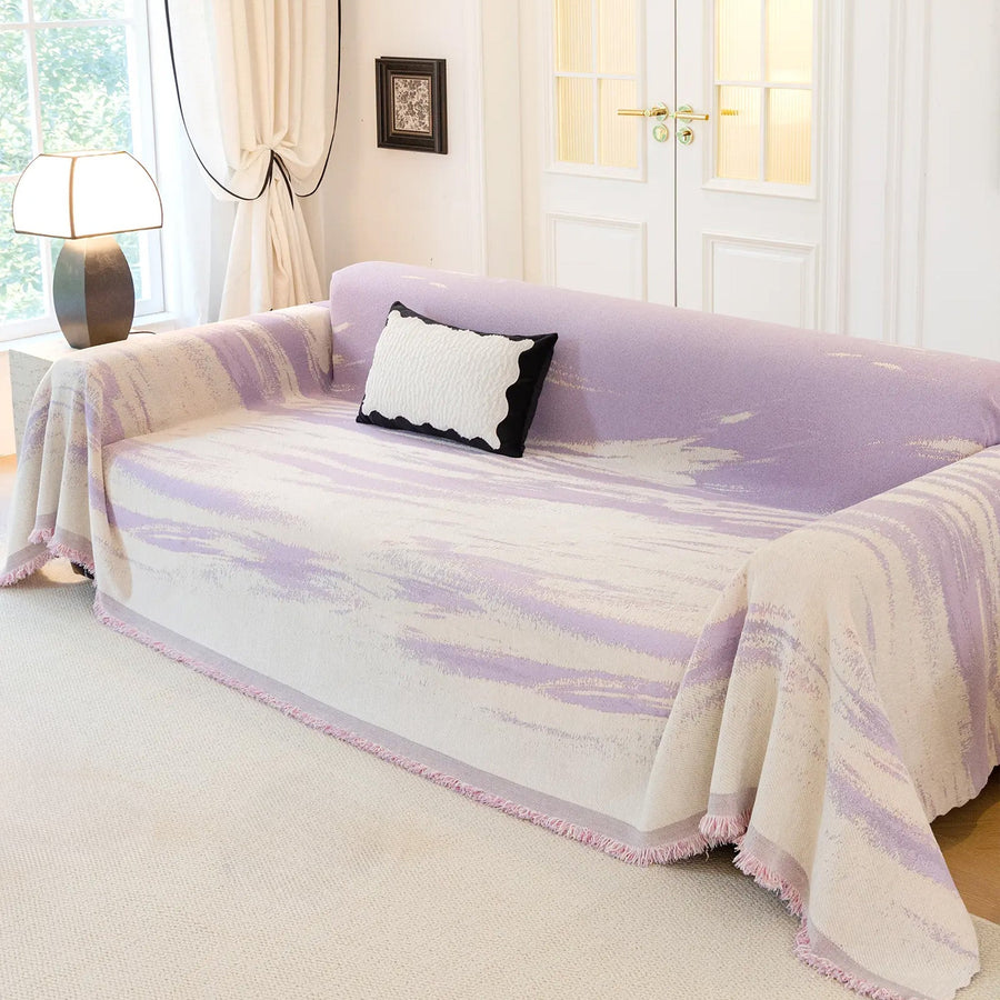 Lavender Drift Brushwave Chenille throw over a sofa in a bright paneled room with a cushion and lamp