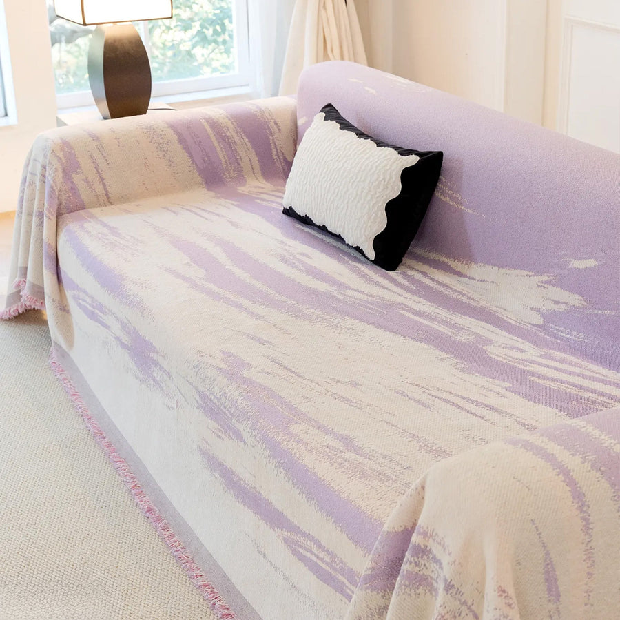 Angled view of Lavender Drift Brushwave Chenille throw on a sofa seat, soft brushstroke waves and cushion