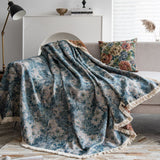Blue Bouquet throw cascading over a couch in soft folds with a floral cushion and lamp