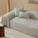 Charcoal Gray Classic Pinstripe throw on a sofa corner with square and lumbar cushions, angled view with wood side table