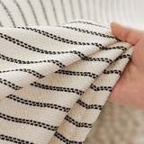 Hand holding Charcoal Gray Classic Pinstripe throw showing the cream woven fabric and fine charcoal stripes