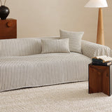 Charcoal Gray Classic Pinstripe throw draped over a sofa beside a wood nightstand and floor lamp, angled view