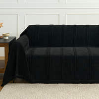 Ebony elegance Classic Striped black throw covering a sofa beside a wood side table, tufted stripe texture