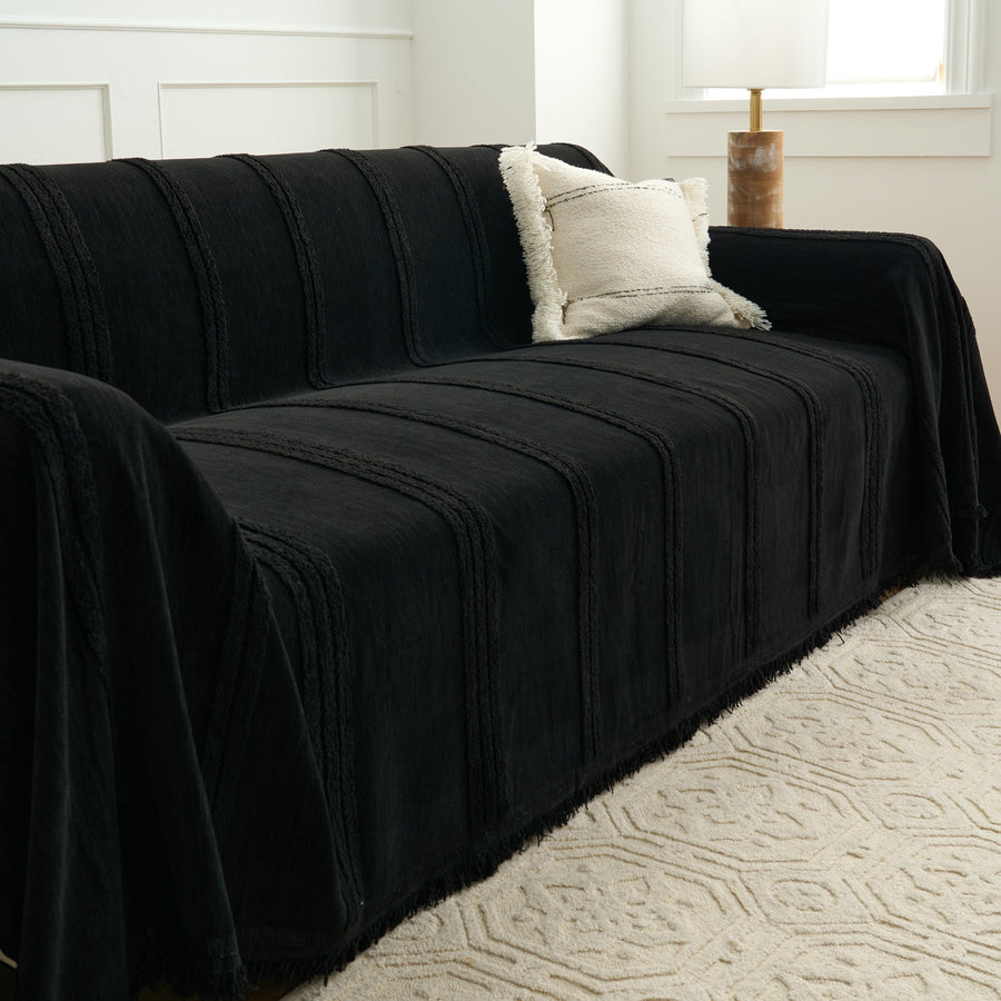 Angled view of the Classic Striped ebony elegance throw over a sofa with a cream boucle cushion
