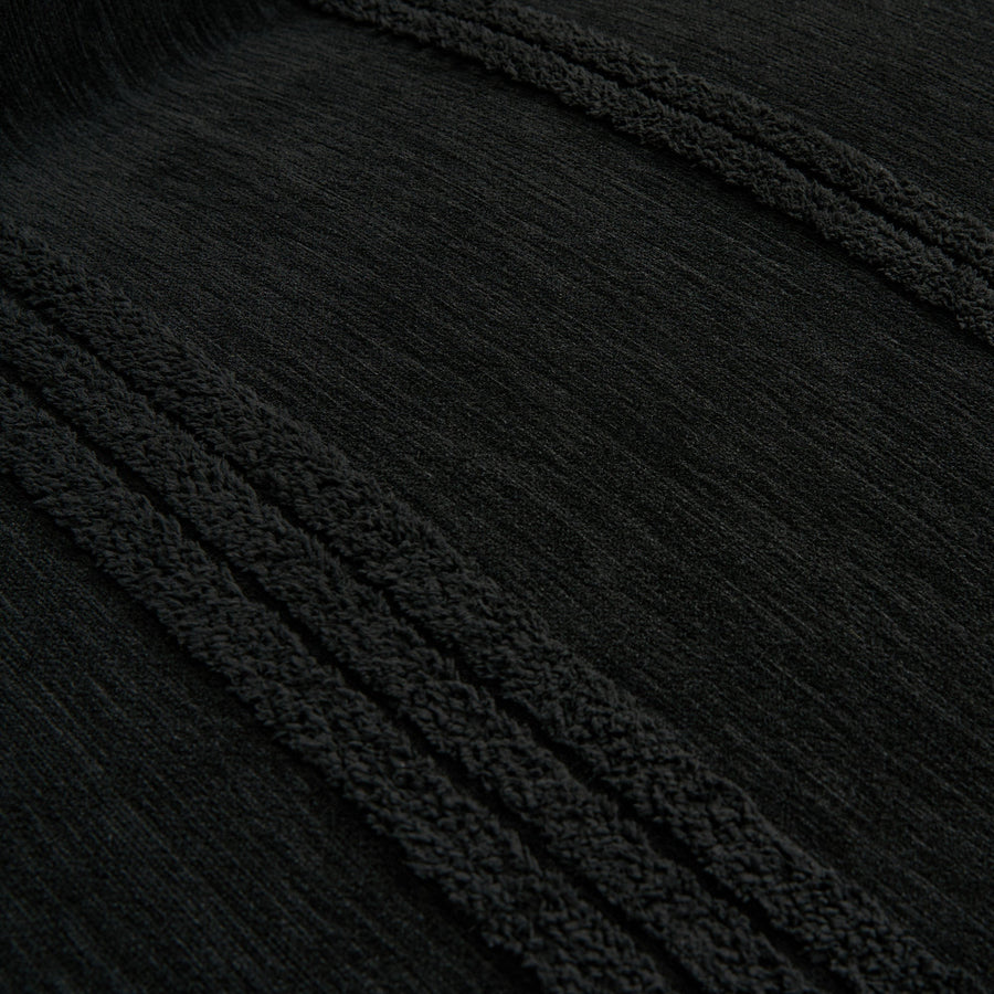 Macro close-up of the ebony elegance throw's raised black tufted stripes and soft woven texture