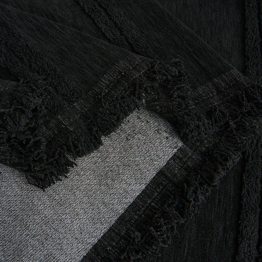 Detail of the ebony elegance Classic Striped throw's fringed corner folded over the sofa