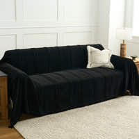 Ebony elegance Classic Striped black throw styled on a sofa in a bright room with a boucle cushion and lamp