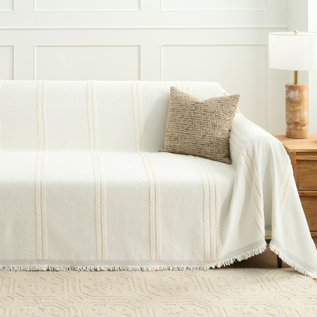 Ivory Whisper Classic Striped throw styled on a sofa in a bright room with a woven cushion and wooden side lamp