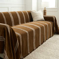 Mocha Harmony Classic Striped throw over a sofa seat and arm with a fringed hem beside a lamp