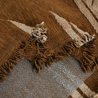 Close-up of Mocha Harmony Classic Striped throw folded, tufted cream stripes and woven base with fringe