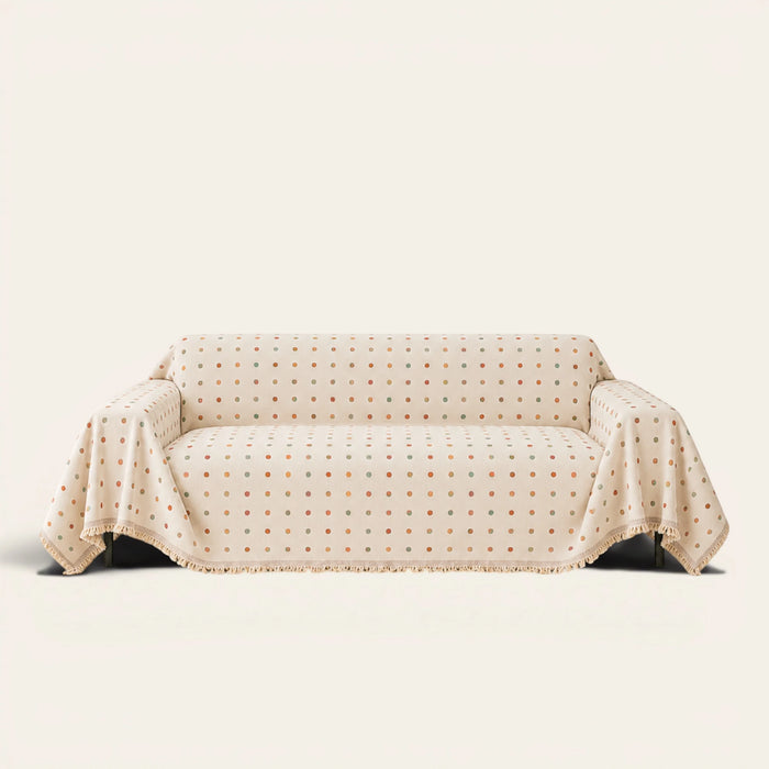 Cream multi Color Dot sofa throw draped over a couch, front view on an ivory backdrop with fringed edge