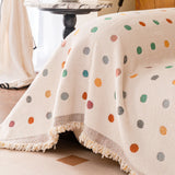 Angled view of the Color Dot cream multi throw draping over the sofa corner with tasseled fringe