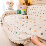 Cream multi Color Dot throw smoothed over a sofa by hand in a cozy living room, fringed hem