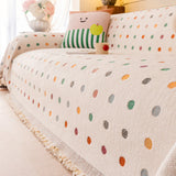 Side angle of the Color Dot cream multi throw cascading over a couch in soft evening light