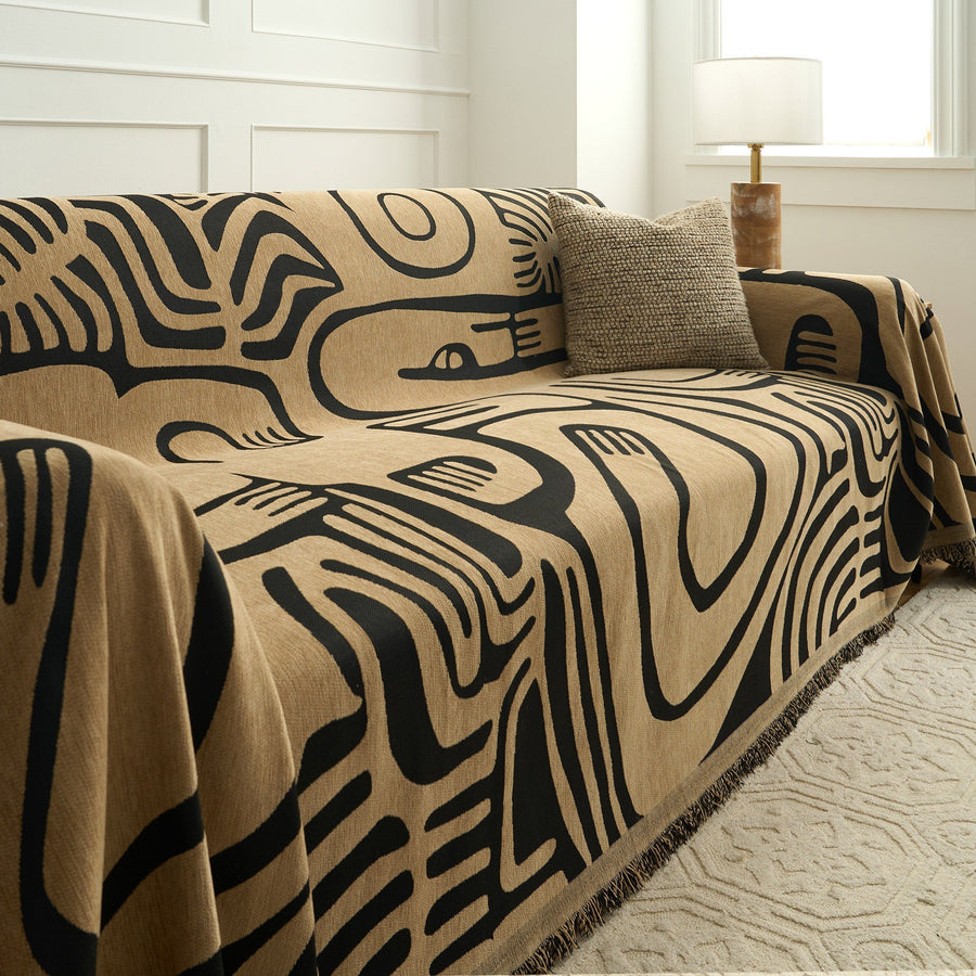 Ebony sand Contemporary Tribal throw draped over a couch showing bold black graphic motifs on sand