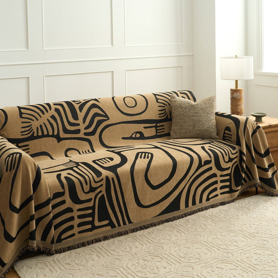 Ebony sand Contemporary Tribal throw styled on a sofa in a bright room with a textured cushion and lamp