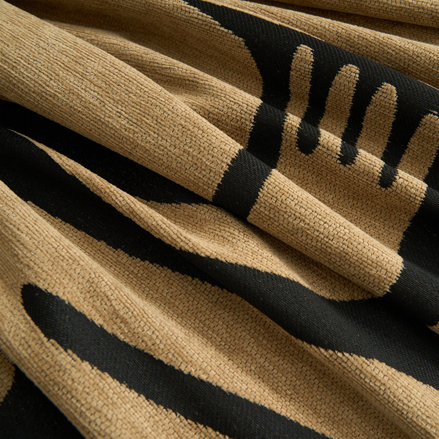 Macro close-up of the ebony sand throw's woven texture and bold black tribal print
