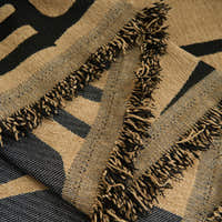 Detail of the ebony sand Contemporary Tribal throw's knotted fringe edge in sand and black