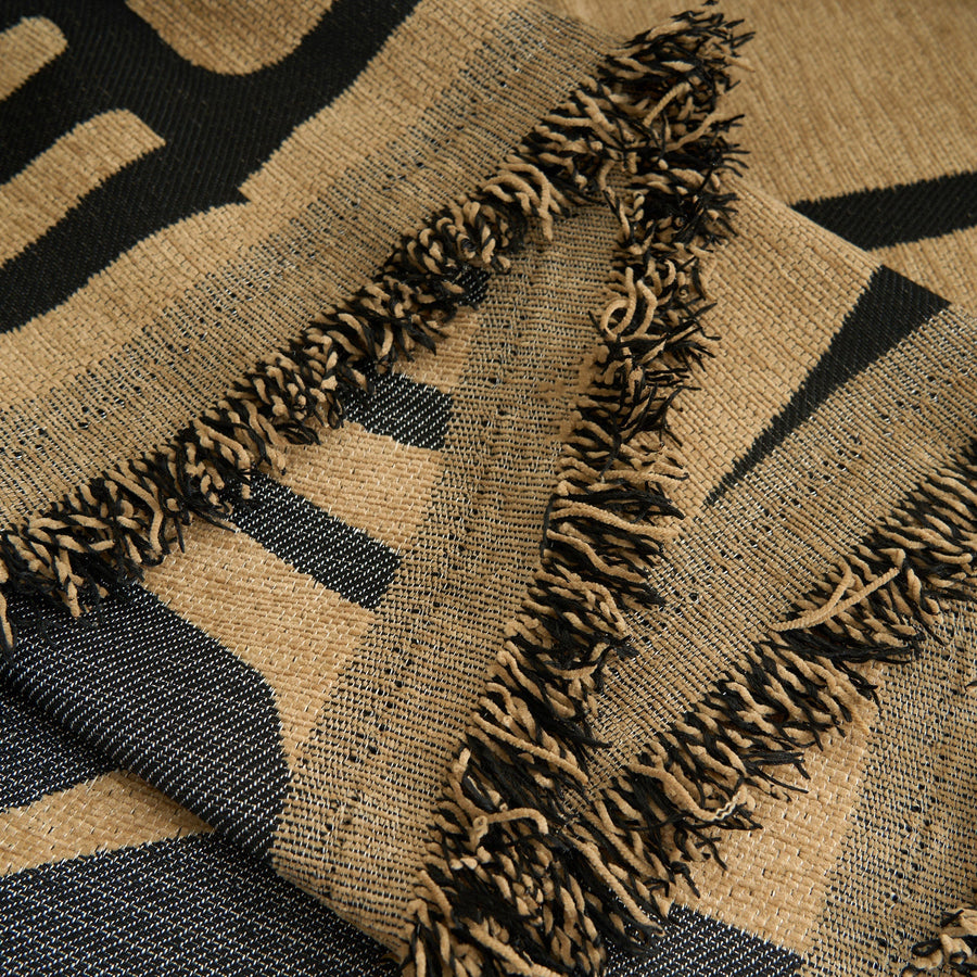 Detail of the ebony sand Contemporary Tribal throw's knotted fringe edge in sand and black