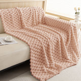 Angled view of the Blush Pink Cozy Chic throw cascading over a sofa by a sunlit window