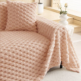 Close view of the plush Blush Pink throw on a sofa corner with a matching cushion and rose vase