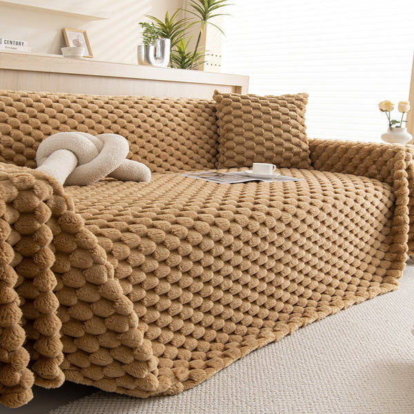 Honeycomb Beige Cozy Chic plush throw styled on a sofa with cushions, cup and plants