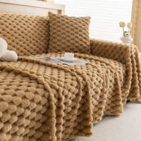 Honeycomb Beige Cozy Chic throw on a sofa with matching pillow, cup and magazine, side angle