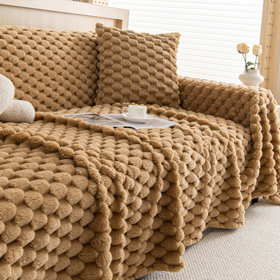 Honeycomb Beige Cozy Chic throw on a sofa with matching pillow, cup and magazine, side angle