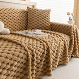 Honeycomb Beige Cozy Chic throw on a sofa with matching pillow, cup and magazine, side angle